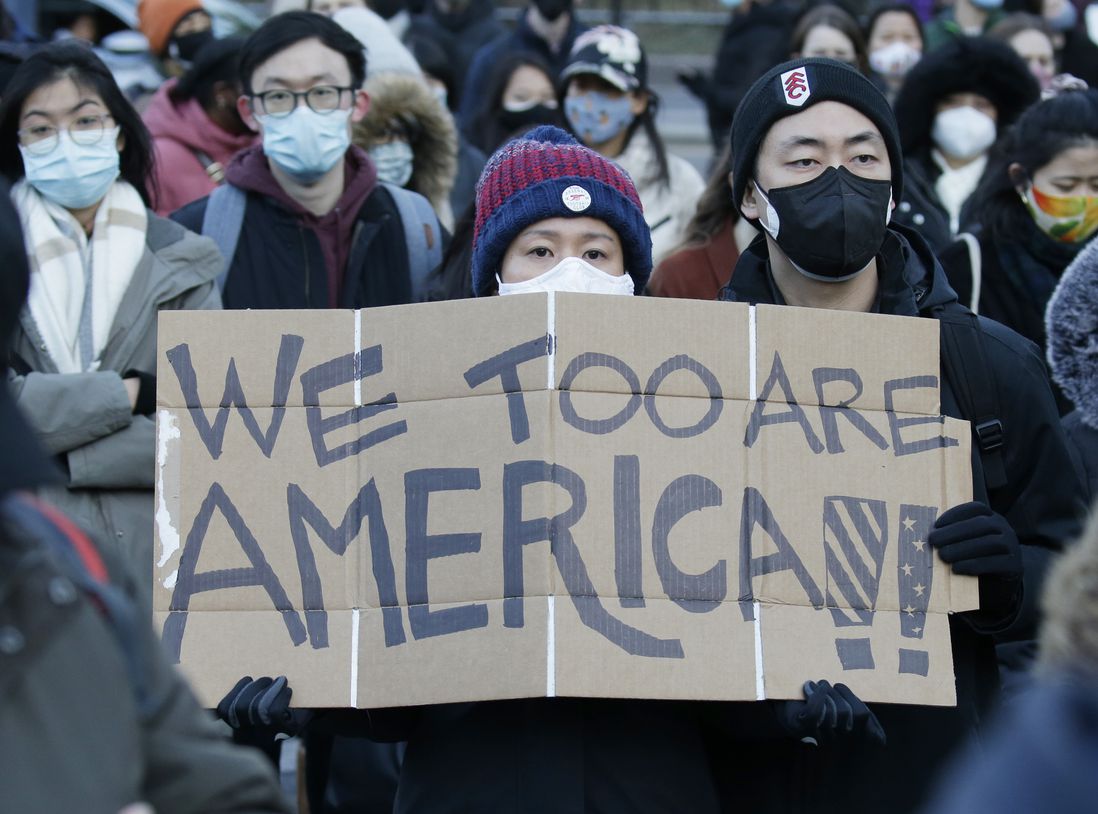 A woman holds a sign that says 'We Too Are America"
